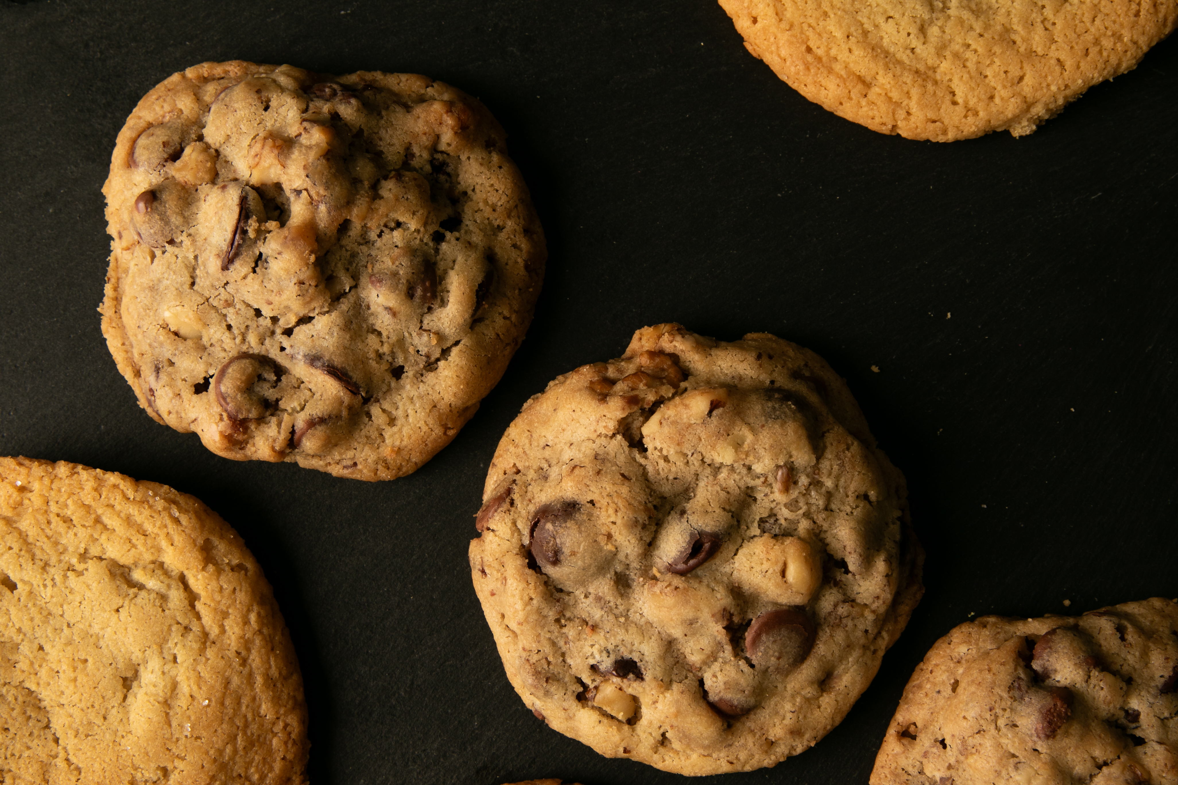 Chocolate chip cookies with nuts on dark surface